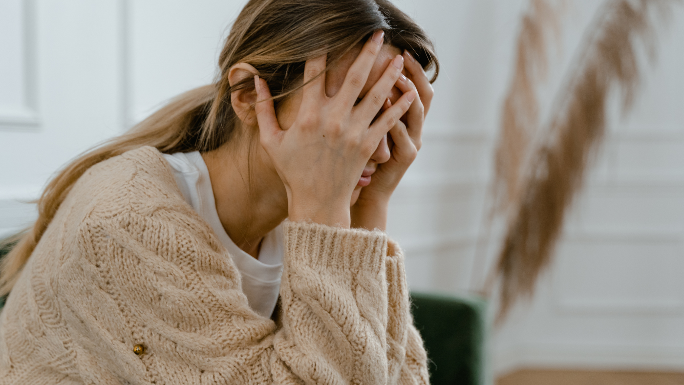 Une femme stressée se tenant la tête, ce qui peut affecter la santé de ses cheveux.