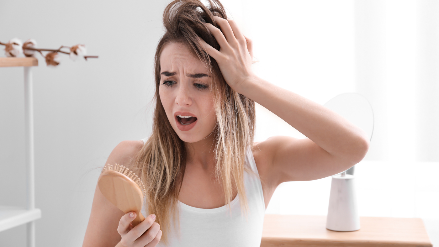 Une femme préoccupée touche doucement ses cheveux, affectée par leur chute.